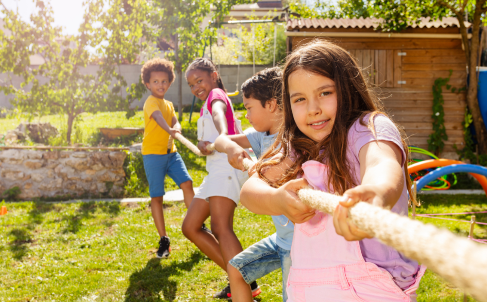 A group of four children are playing tug-of-war outsite.