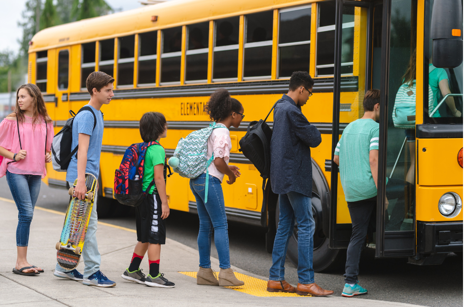 Students are lined up getting onto a school bus.