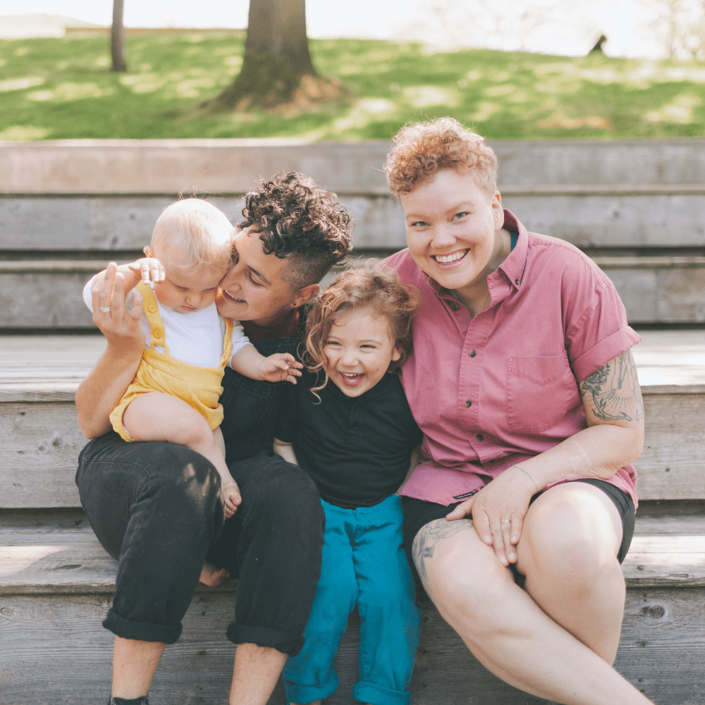 LGBTQ family sitting on a park bench